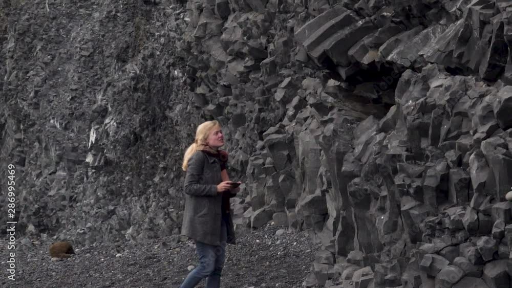 Tourist taking photos of the black volcanic rocks and sand at Dyrhólaey Tourist taking photos of the black volcanic rocks and sand at Dyrhólaey