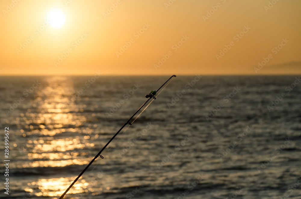 Fishing rodes pointing at sunset on Newport Beach pier Fishing rodes pointing at sunset on Newport Beach pier