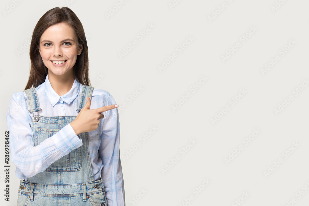 Smiling teen girl pointing at blank copy space aside Smiling teen girl pointing at blank copy space aside