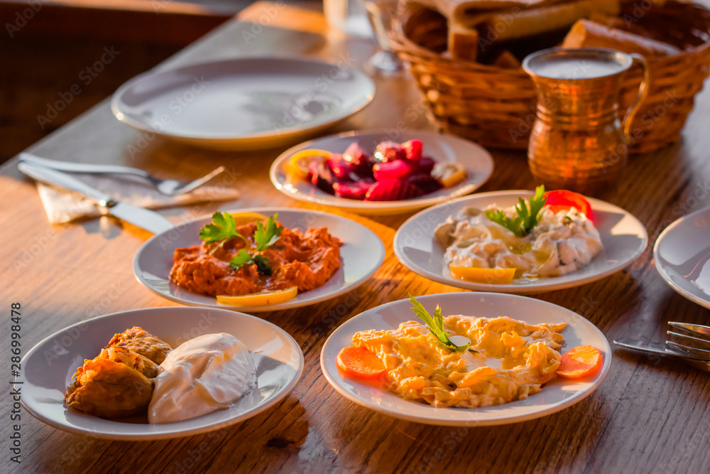 traditional turkish appetizers on table in evening sun light and ayran in a copper glass