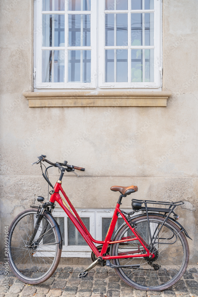red vintage bicycle parked on stone wall with a window