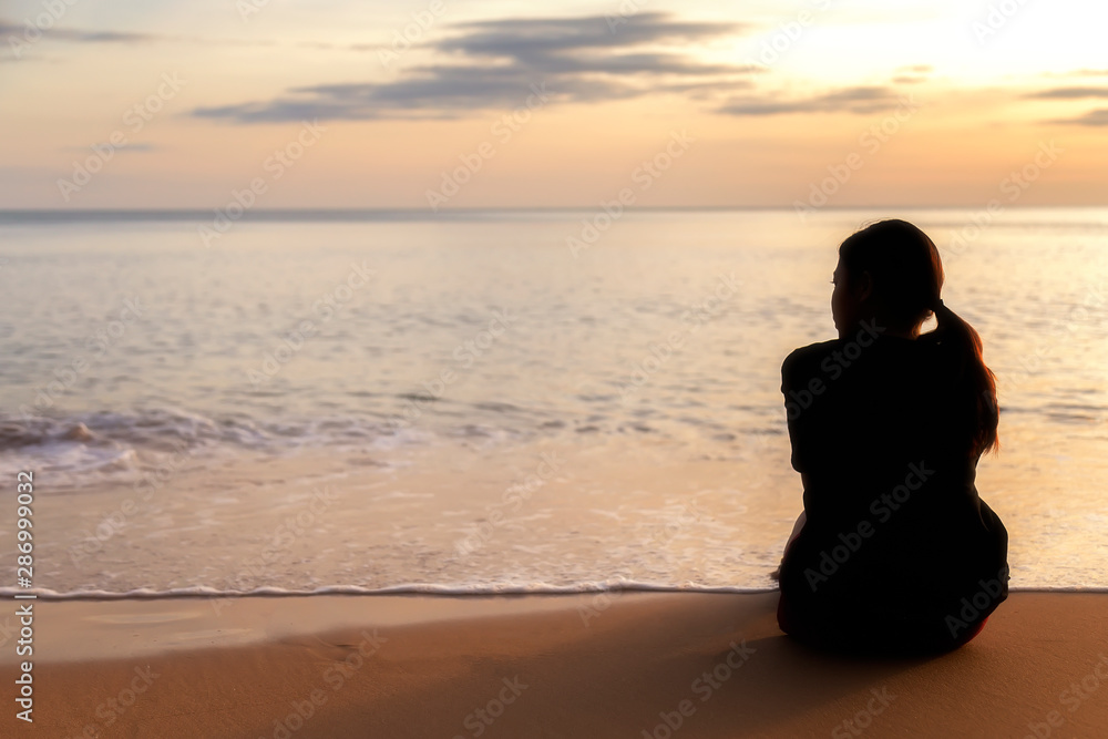 Romantic  girl are sitting on the beach for looking sunset over the sea at Chantaburi province , Thailand. Asian women in black dress are looking the sunset in the evening.