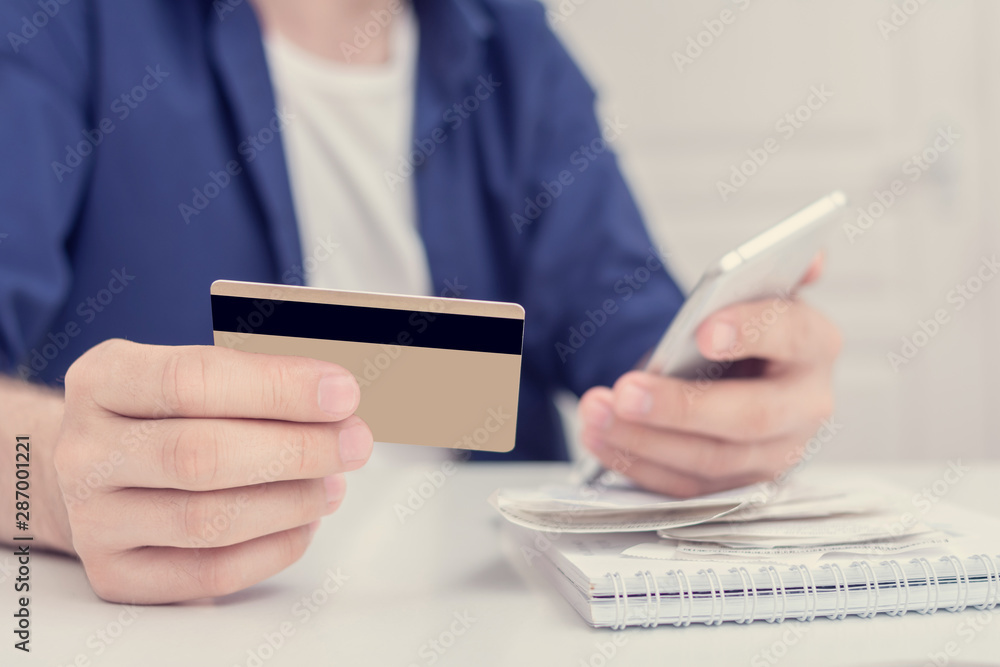 Man pays bills via smart phone, men's hands, cropped image, closeup, toned Man pays bills via smart phone, men's hands, cropped image, closeup, toned