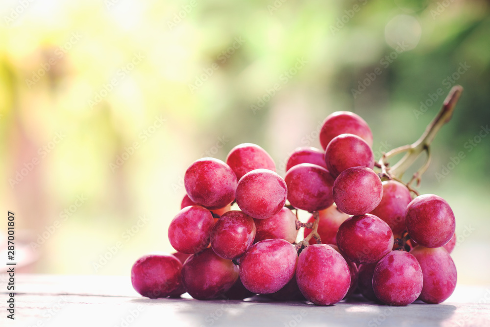 Bunches of ripe red grape on wooden wooden texture, natural green background Bunches of ripe red grape on wooden wooden texture, natural green background
