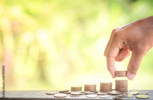Close up of hand male putting coins to stack of coins. Saving money and finance business investment concept.