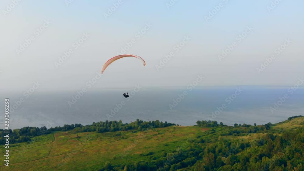 Paraglider is floating over the forest and the water Paraglider is floating over the forest and the water