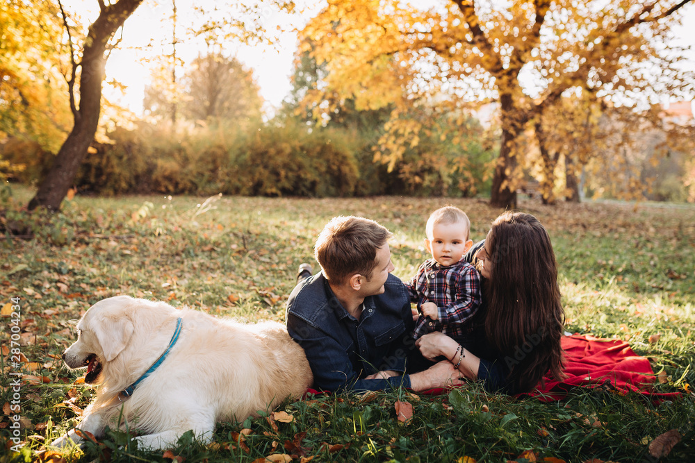 Fototapeta premium Family with a child and a golden retriever in an autumn park
