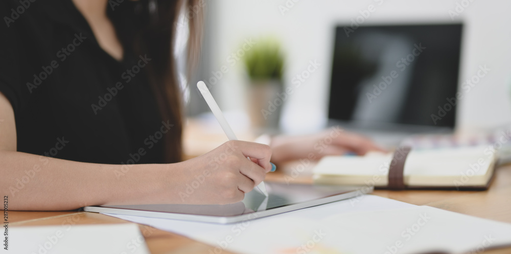 Close-up view of young female designer editing her concept with tablet Close-up view of young female designer editing her concept with tablet