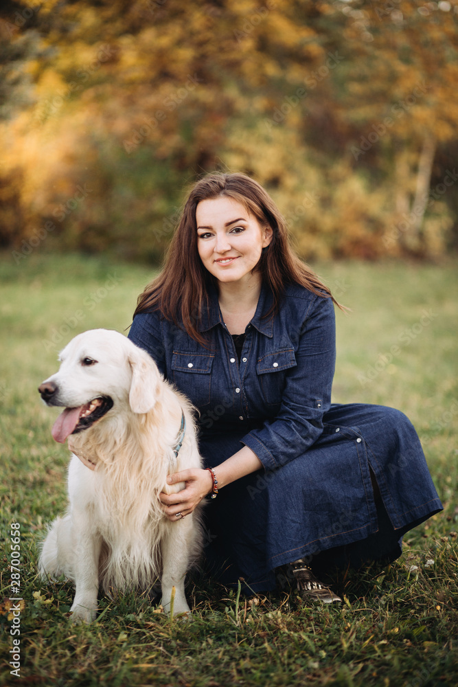 Young woman with a golden retriever in a beautiful autumn park