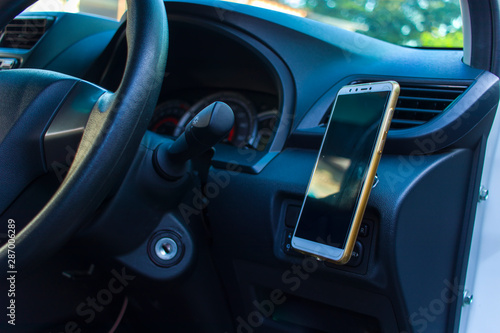 Smartphone in a car use for Navigate or GPS. Driving a car with Smartphone in holder. Mobile phone Blank empty screen. copy space. Empty space for text. car interior details.