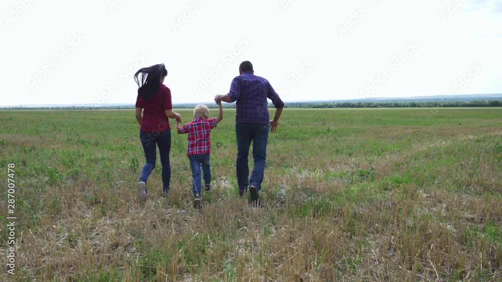 A happy family runs forward on the green grass on a warm summer day. A happy family runs forward on the green grass on a warm summer day.