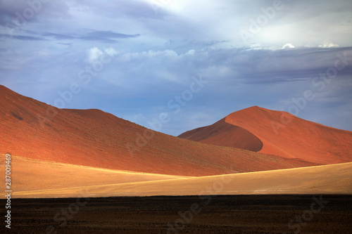 Namibia landscape. Big orange dune with blue sky and clouds  Sossusvlei  Namib desert  Namibia  Southern Africa. Red sand  biggest dune in the world. Travelling in Africa.