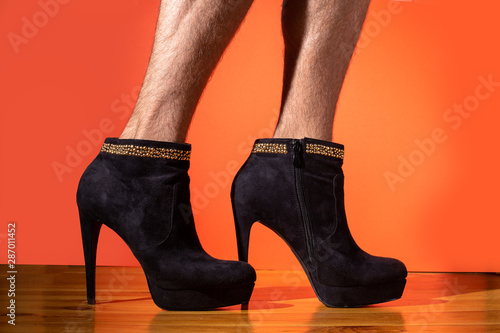 Man with hairy legs on high heels on orange background