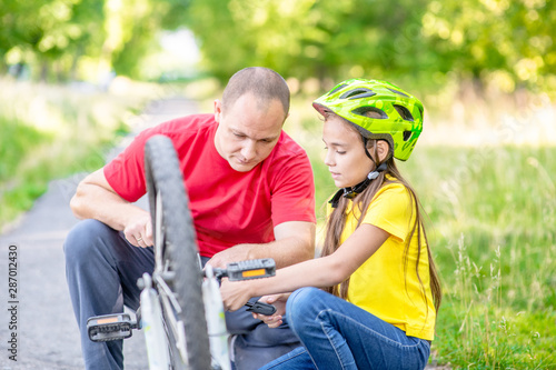 Happy family. Father helps daughter to pump bicycle wheel in summer park © Ermolaev Alexandr