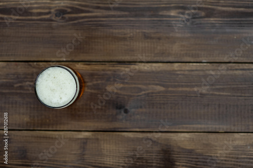 Glass of beer on dark wooden background. Top view. Empty space for text