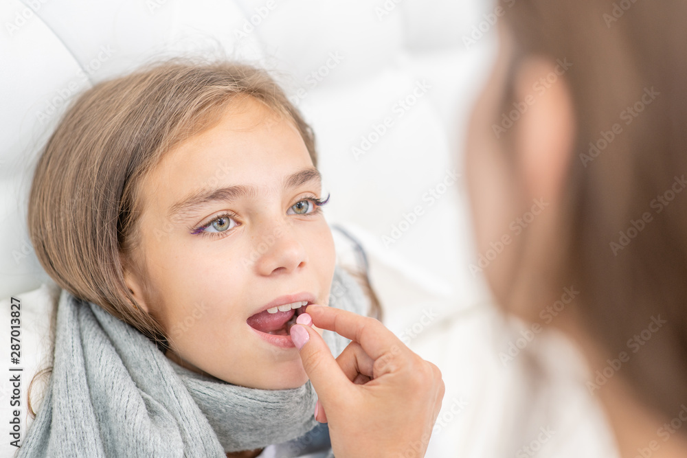 Mother giving pill to her sick daughter at home Mother giving pill to her sick daughter at home