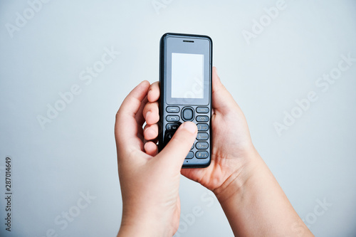 Child holding a traditional mobile phone on white backround