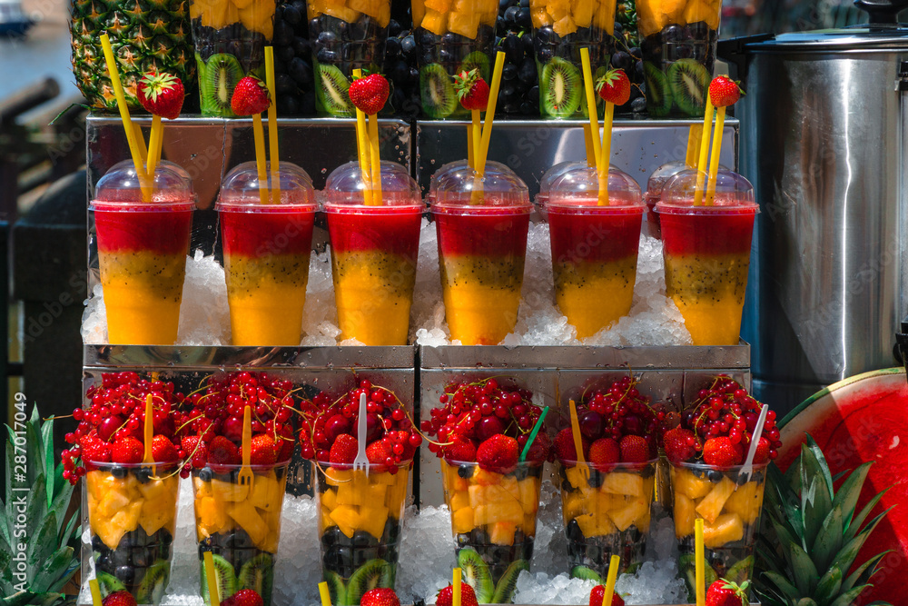 Fototapeta premium Multifruit set. Chilled glass with kiwi, pineapple, grapes, strawberries, berries. beautifully served desserts for tourists. ice and spoons. delicious stand healthy summer treats rich in vitamins