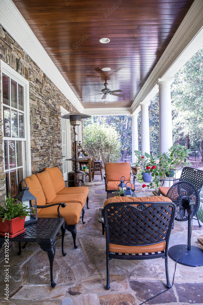 Φωτογραφία Outdoor Stone Patio Porch of large home estate with orange rust colorseating
