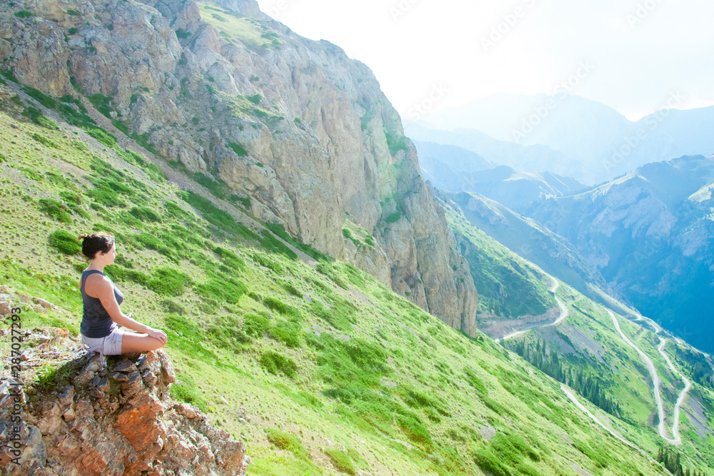Woman meditates sitting on top in the mountains.