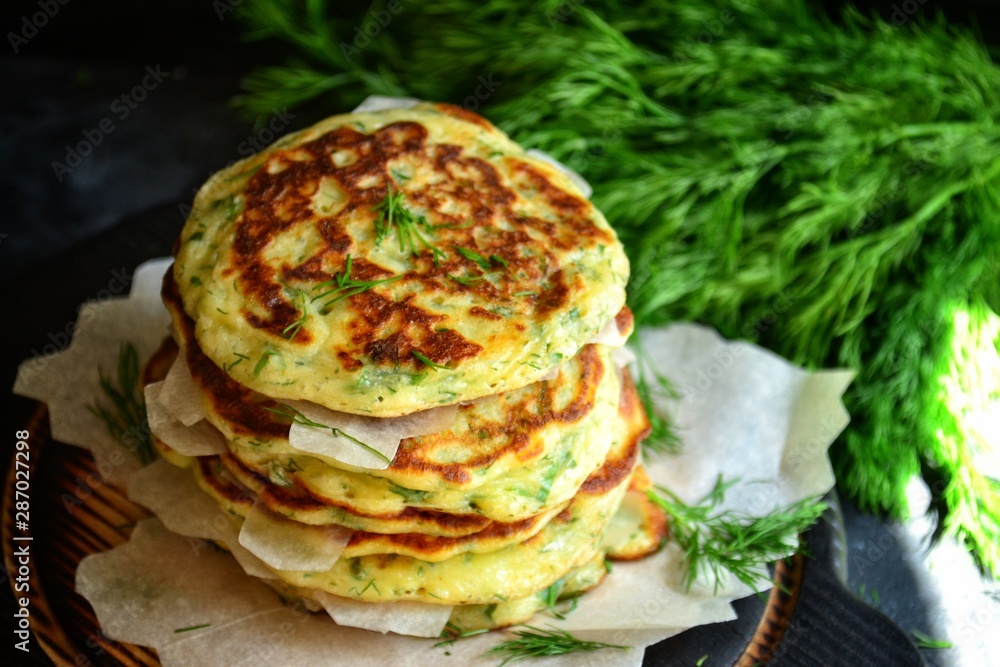 Appetizing pancakes on a wooden board. A photo of food in low key. Pancakes with parsley and chives. Ukrainian and Russian cuisine. Food on a black background. Pancake week. Appetizing pancakes on a wooden board. A photo of food in low key. Pancakes with parsley and chives. Ukrainian and Russian cuisine. Food on a black background. Pancake week.