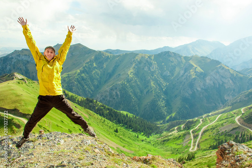 A man with his hands raised in a jump on the background of mountains.