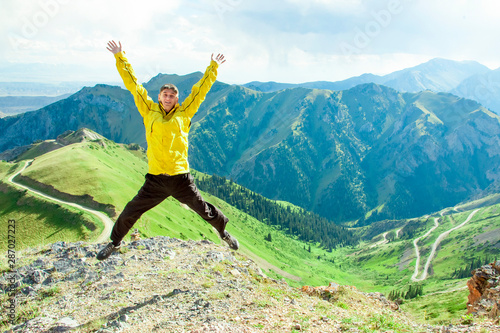 Smiling man jumps up on a background of mountains.