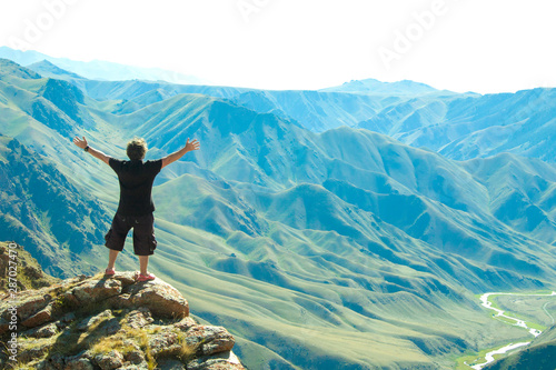 A man with outstretched arms standing in the mountains.