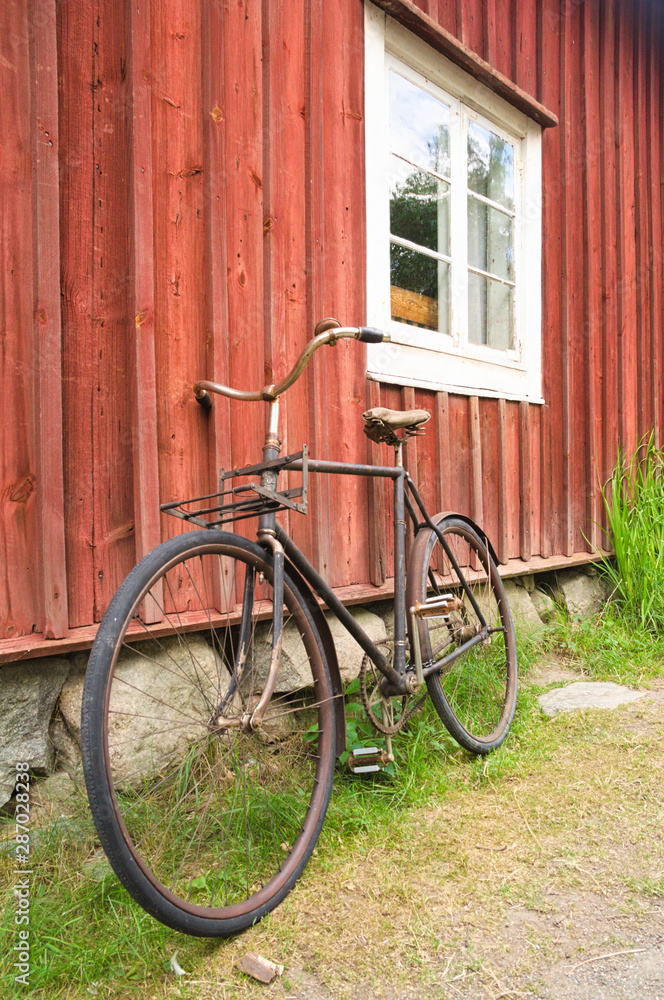 Old bicycle leaning against wooden wall of a house