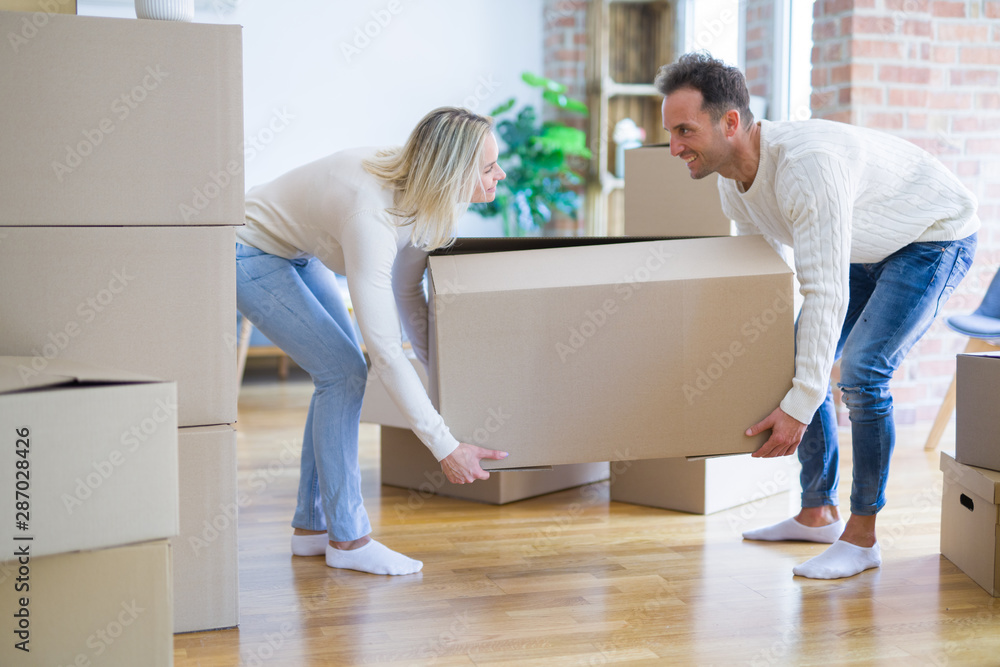 Young beautiful couple moving cardboard boxes at new home Young beautiful couple moving cardboard boxes at new home
