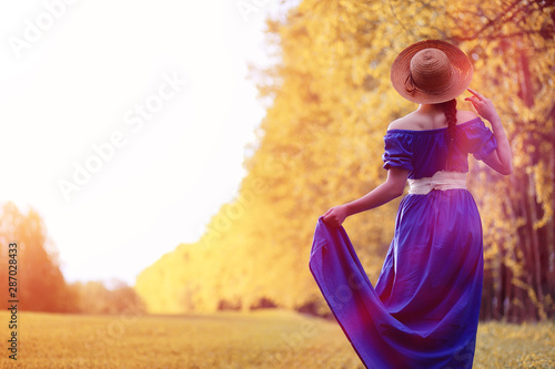 Young beautiful girl in dresses on nature. A girl in a hat walks in the park. Young woman on a picnic with a basket outside the city.