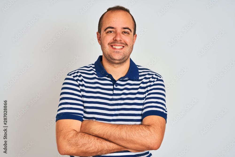 Young man wearing casual striped polo standing over isolated white background happy face smiling with crossed arms looking at the camera. Positive person. Young man wearing casual striped polo standing over isolated white background happy face smiling with crossed arms looking at the camera. Positive person.