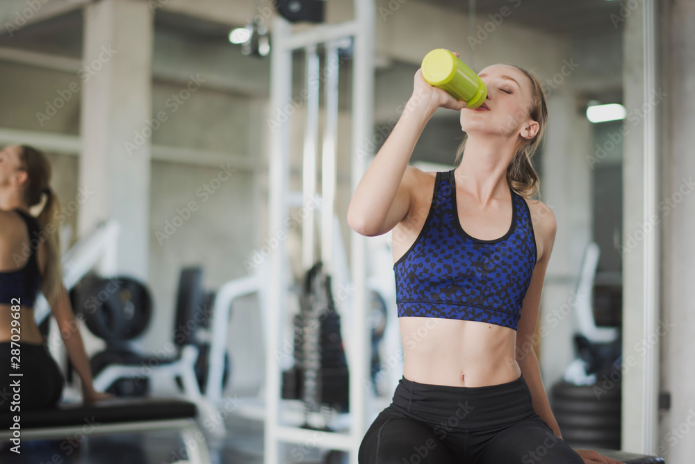 Premium Photo  A young slim blonde woman drinks water from a large  transparent glass after training