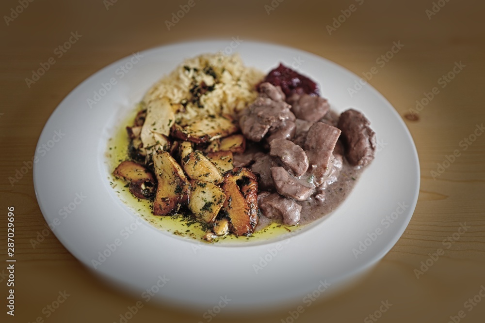 a delicious meal is roasted boletus edulis, venison goulash with rice and sauce