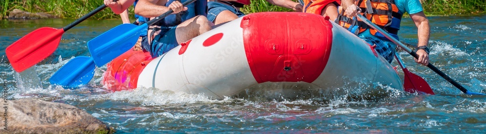 Naklejka premium Rafting trip. Close up view of oars with splashes of water. Rowers make an effort to overcome the turbulent river. The concept of teamwork, healthy lifestyle.