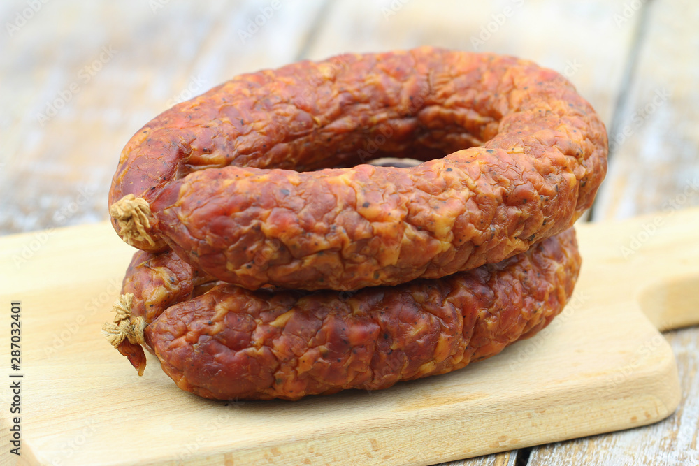 Fototapeta premium Traditional Polish smoked sausage on wooden board, closeup