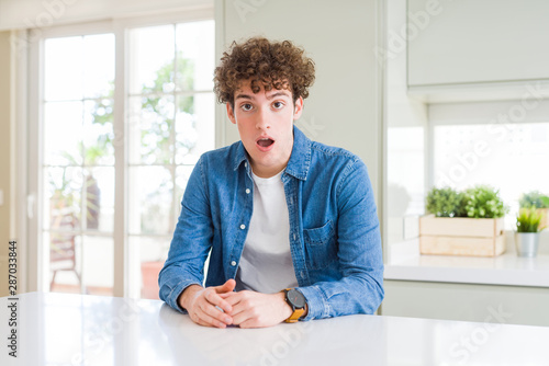 Young handsome man wearing casual denim jacket at home afraid and shocked with surprise expression, fear and excited face. © Krakenimages.com