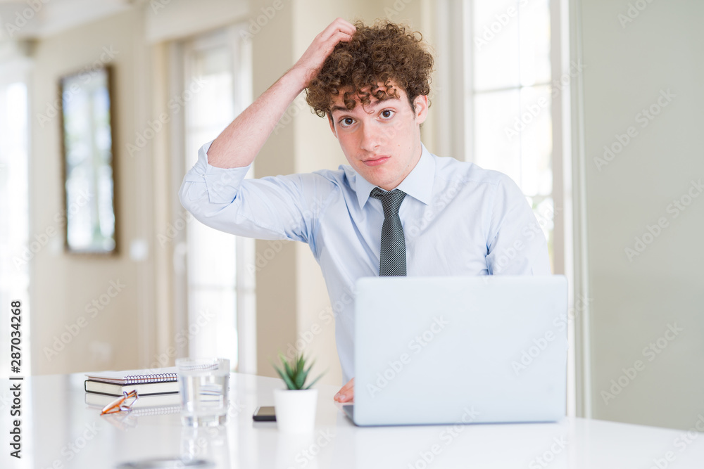 Young business man working with computer laptop at the office confuse and wonder about question. Uncertain with doubt, thinking with hand on head. Pensive concept.