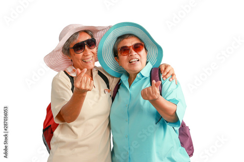 Happy elderly buddy traveling together, senior Asian women tourist with backpack wear hat and sunglasses isolated on white background. Mature female travelers feel excited and joyful with journey trip