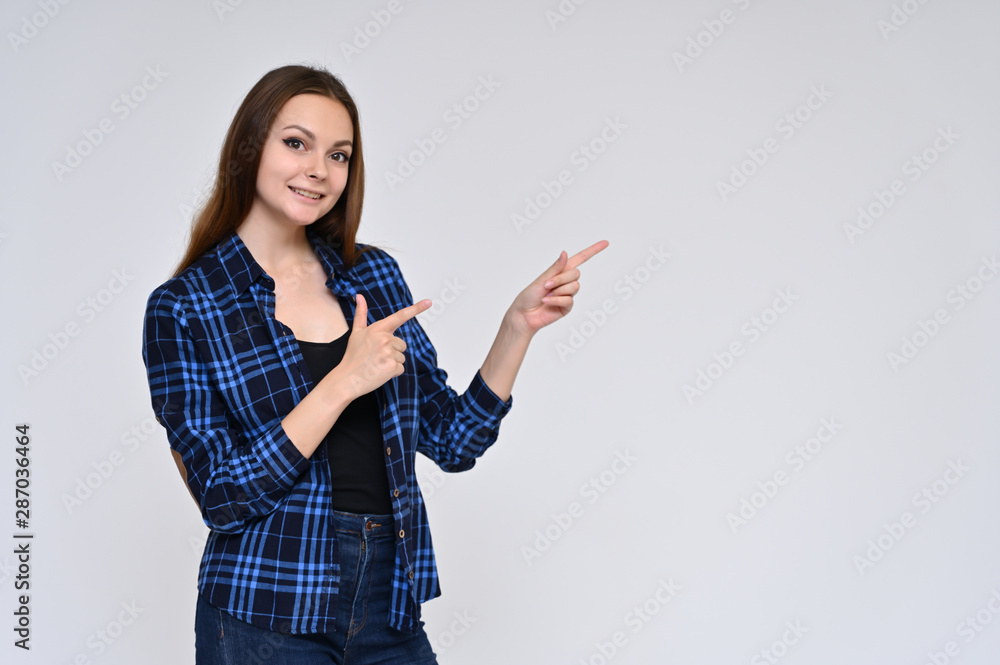 Portrait of a cute brunette girl, a young woman with beautiful curly hair in a blue shirt on a white background. Smiling, talking with emotions, showing hands to the sides. Portrait of a cute brunette girl, a young woman with beautiful curly hair in a blue shirt on a white background. Smiling, talking with emotions, showing hands to the sides.