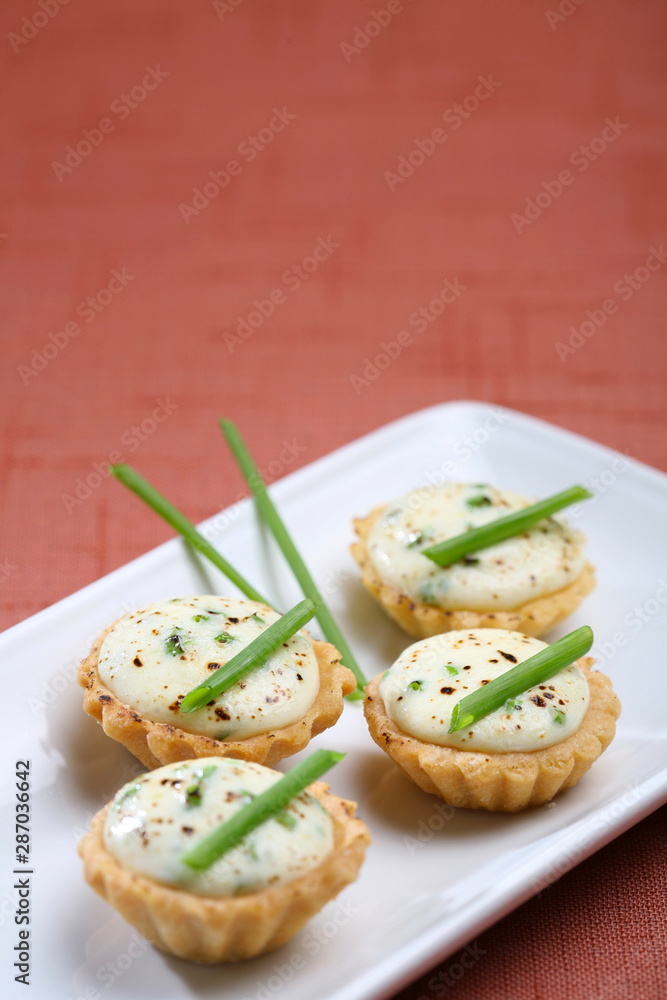 Mini cheese tartlets, presentation of catering for celebration. Served on colored tablecloth. Mini cheese tartlets, presentation of catering for celebration. Served on colored tablecloth.