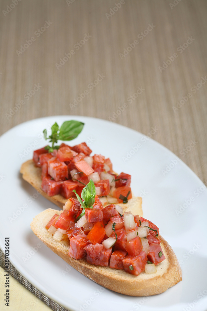 Toasted bread with sausage, presentation of catering for celebration. Served on colored tablecloth. Toasted bread with sausage, presentation of catering for celebration. Served on colored tablecloth.
