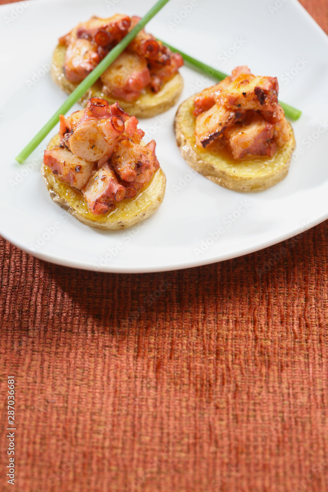 Potato starters with octopus, presentation of catering for celebration. Served on colored tablecloth. Potato starters with octopus, presentation of catering for celebration. Served on colored tablecloth.