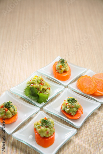 Carrot entrees with guacamole, presentation of catering for celebration. Served on colored tablecloth.