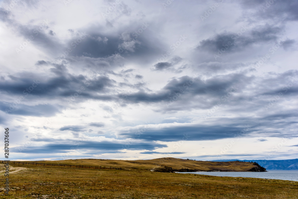 Fototapeta premium Lake Baikal, trees and mountains of Siberia with beautiful sky and clouds, Russia Oklhon island