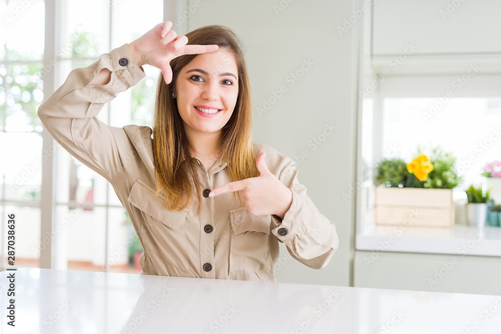 Beautiful young woman at home smiling making frame with hands and fingers with happy face. Creativity and photography concept. Beautiful young woman at home smiling making frame with hands and fingers with happy face. Creativity and photography concept.