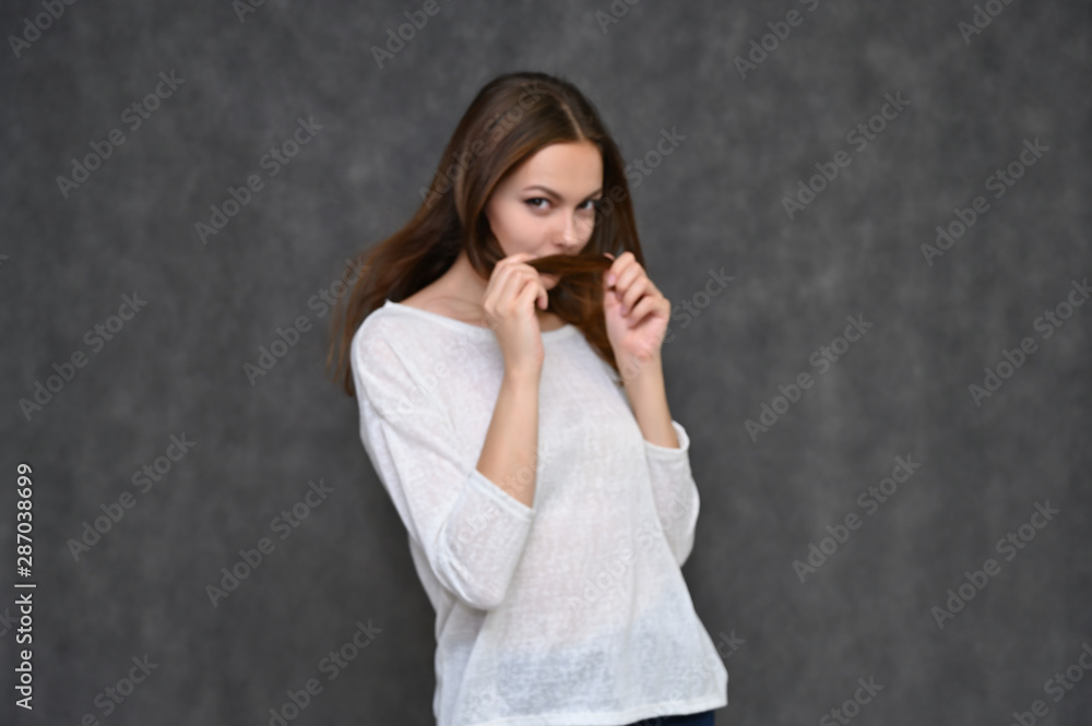 Portrait of a cute brunette girl, a young woman with beautiful curly hair in a white sweater on a gray background. Smiling, talking with emotions, showing hands to the sides. Portrait of a cute brunette girl, a young woman with beautiful curly hair in a white sweater on a gray background. Smiling, talking with emotions, showing hands to the sides.