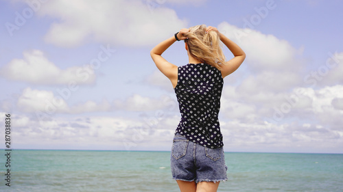 Outdoor summer portrait of young pretty woman looking to the ocean at tropical beach, enjoy her freedom and fresh air
