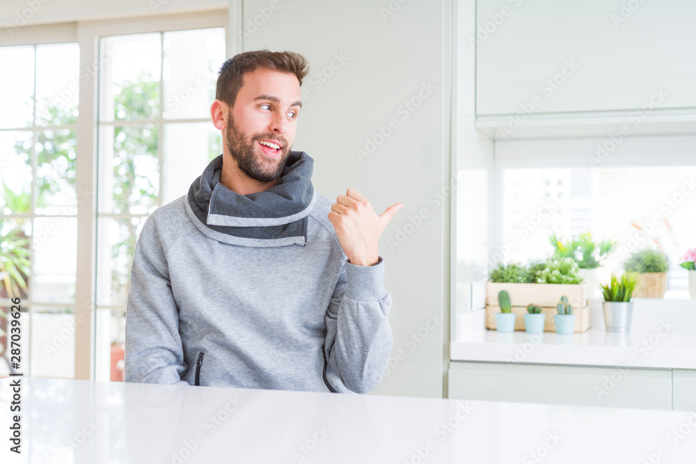 Handsome man at home smiling with happy face looking and pointing to the side with thumb up. Handsome man at home smiling with happy face looking and pointing to the side with thumb up.