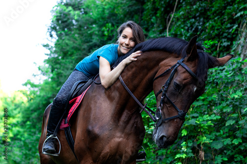 Young beautiful brunette girl cuddles on the horseback in woods. © Andrej
